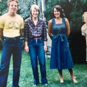 Four people stand in 70s garb posing for a picture