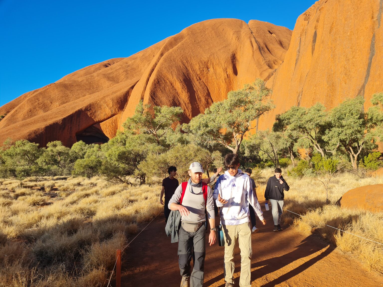 Two student walk with golden mountains and brush seen behind them