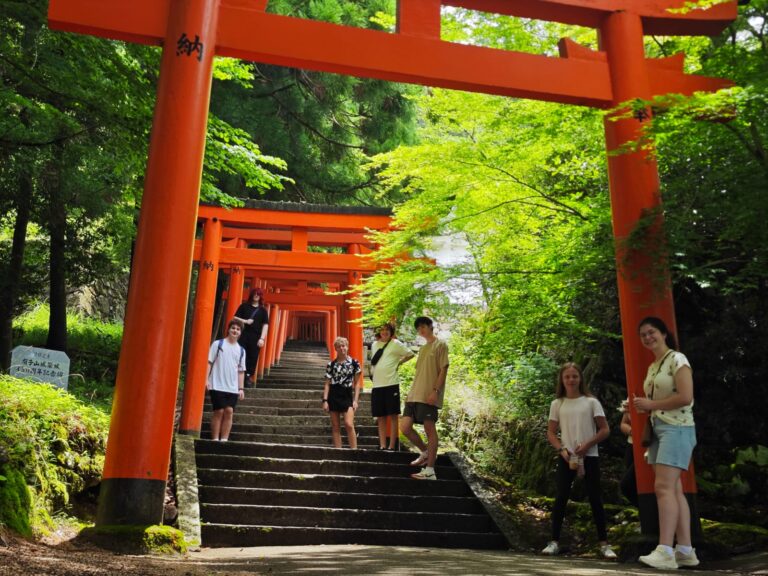 Student through red Tori gates in Toyooka, Japan.