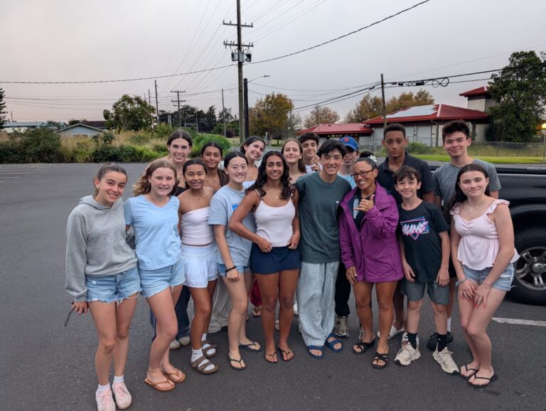 Students stand for a group picture outside on a street 