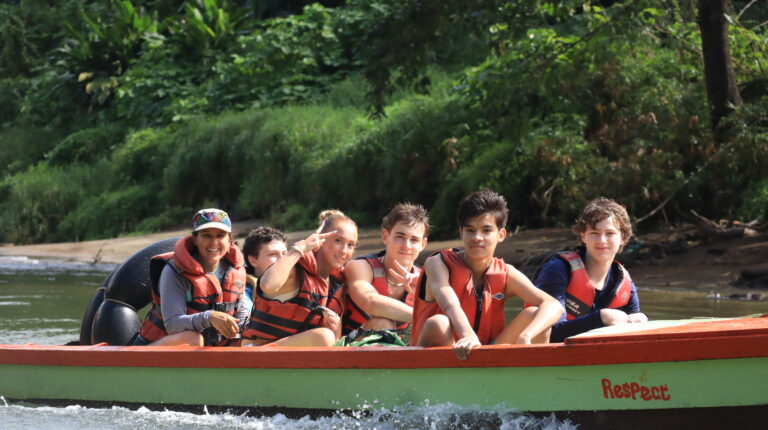Students sit in boat voyaging down the Navua River in the Fijian jungle.