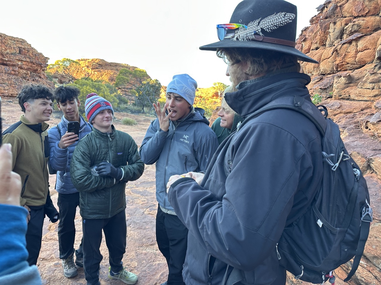Leader stands with three students, one of whom eats vegimite 