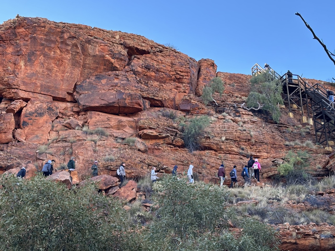 Far away shot of student walking in a line near red stone face 