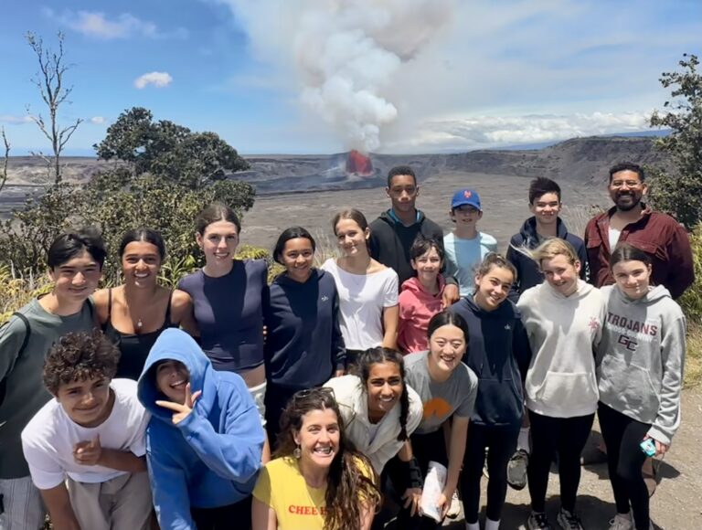 Students pose for a group photo in front of an exploding volcano