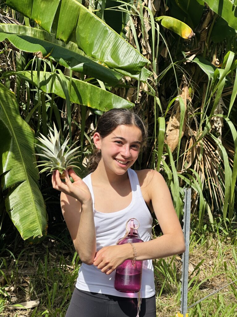 Student holds up a spikey plant and smiles