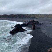 Bright blue waves crash on black sand beach