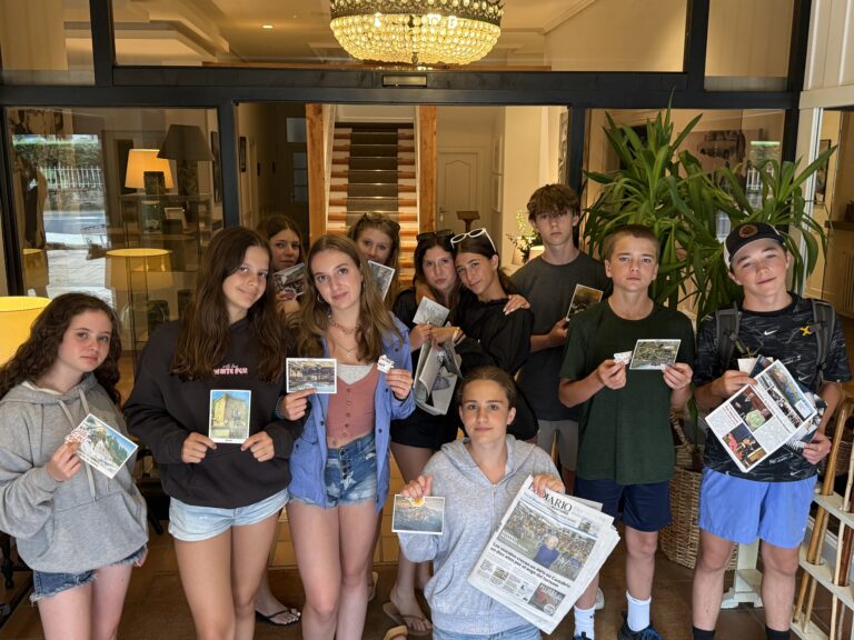Group of students pose for a group photo holding news papers and post cards