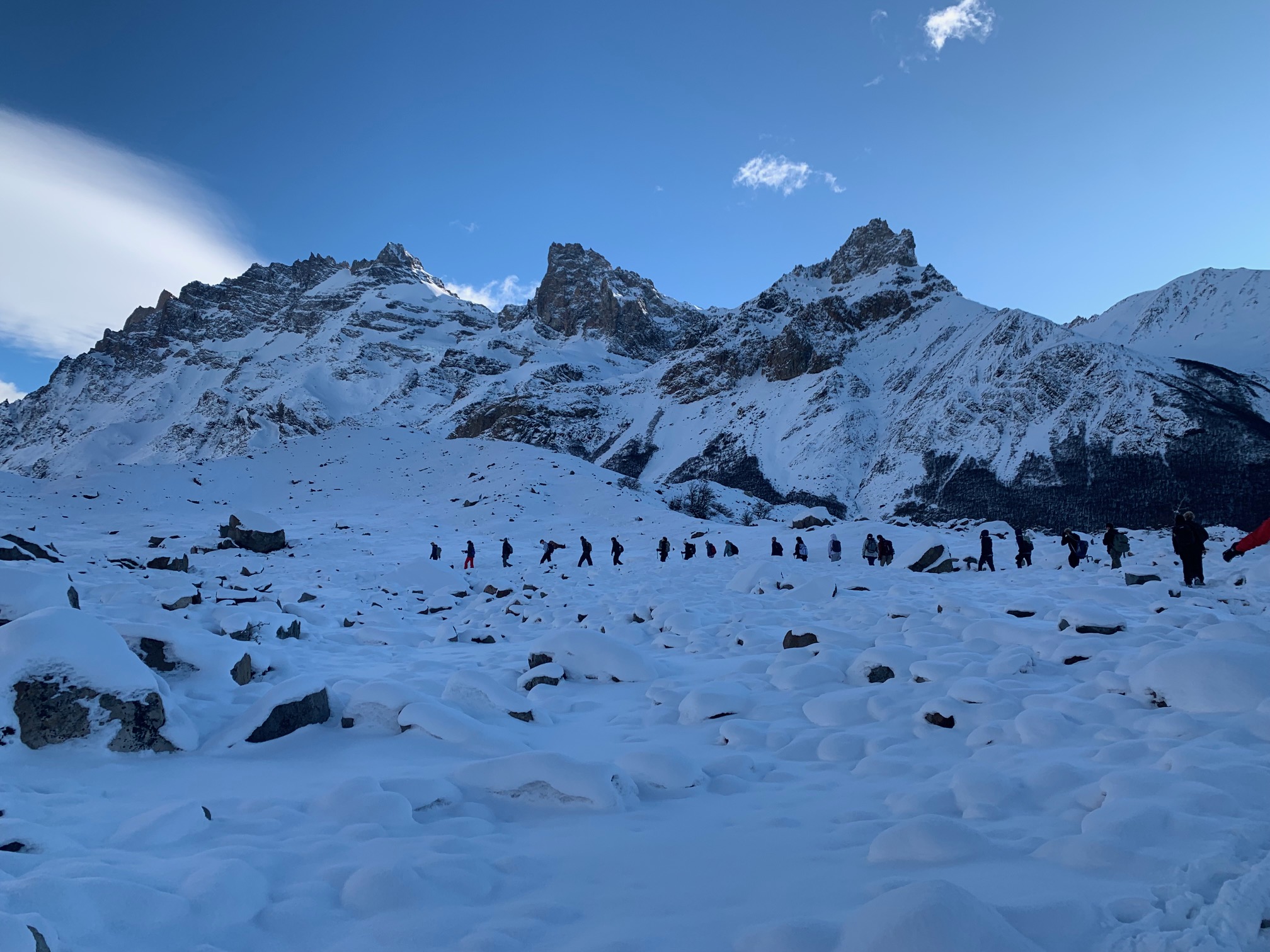 Students walk up snowy Patagonian mountain trail in a line in the distance