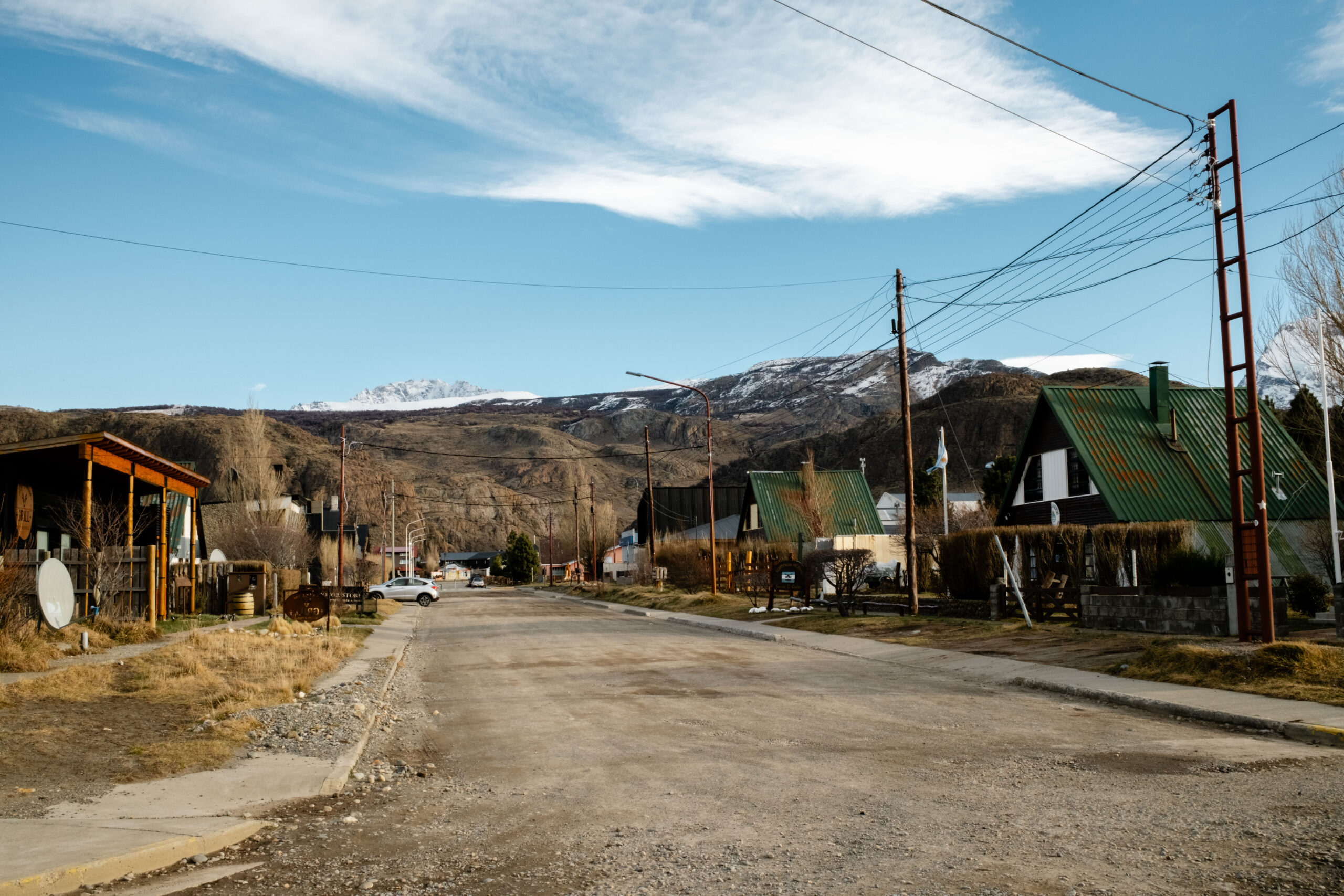 Street in El Chaltén town with paved road and small colorful buildings 