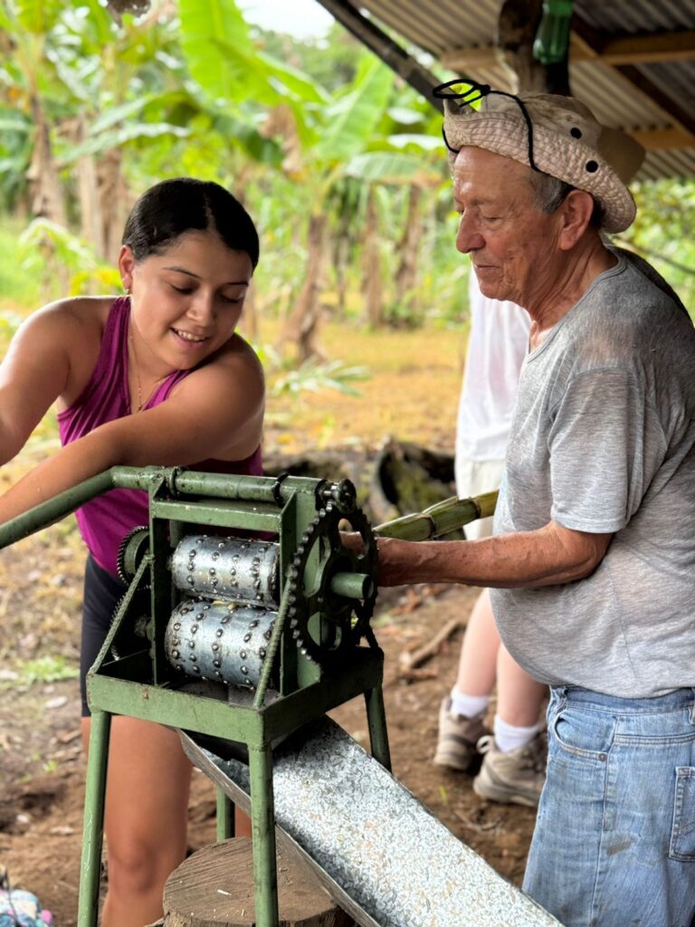 Local instructor lets student crank metal machine to process sugarcane