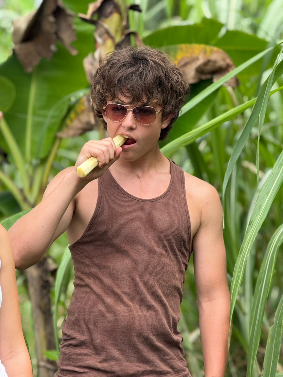Student bites dramatically into a piece of fresh sugarcane