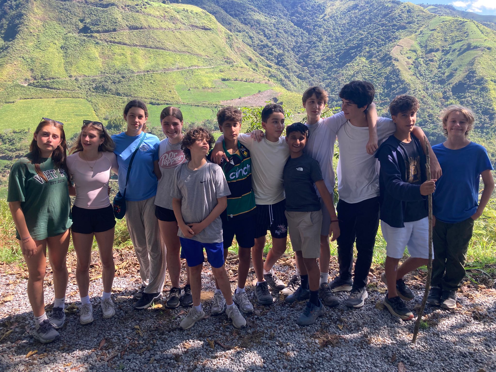 Students pose for a group photo with lush green Ecuadorian mountains in background