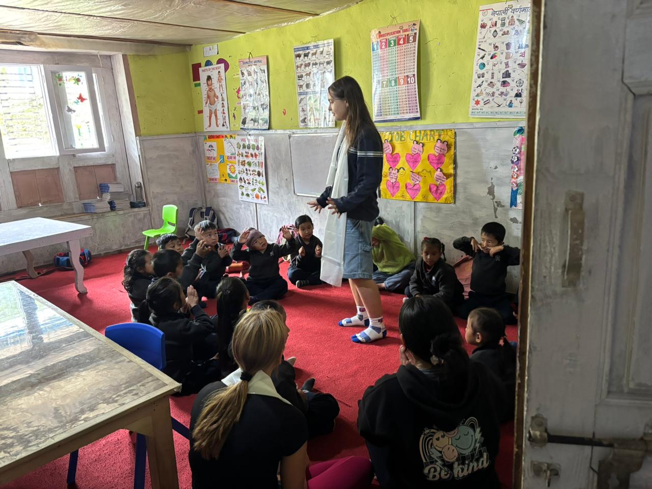 Student stands in front of a classroom while small children sit on the floor for a lesson