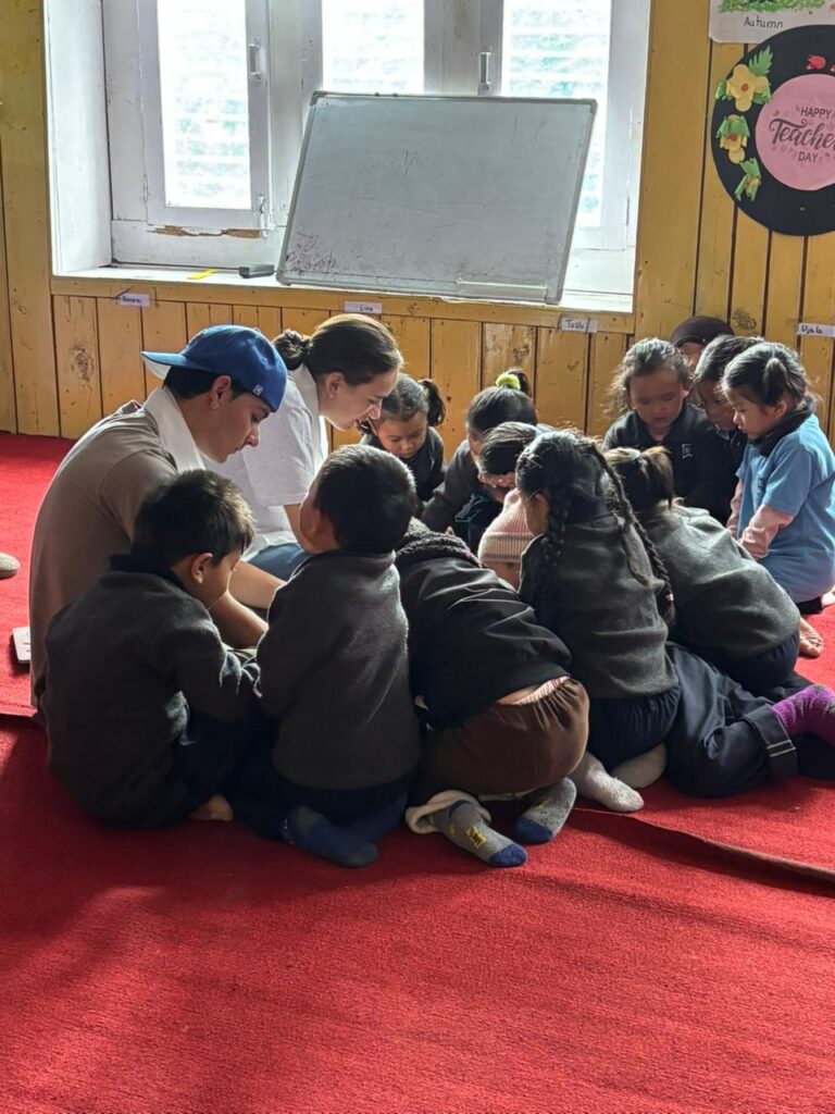 Students helps youn children who circle in close for a lesson