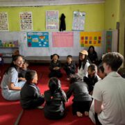 Student smiles widely at small children seated in circle for a lesson