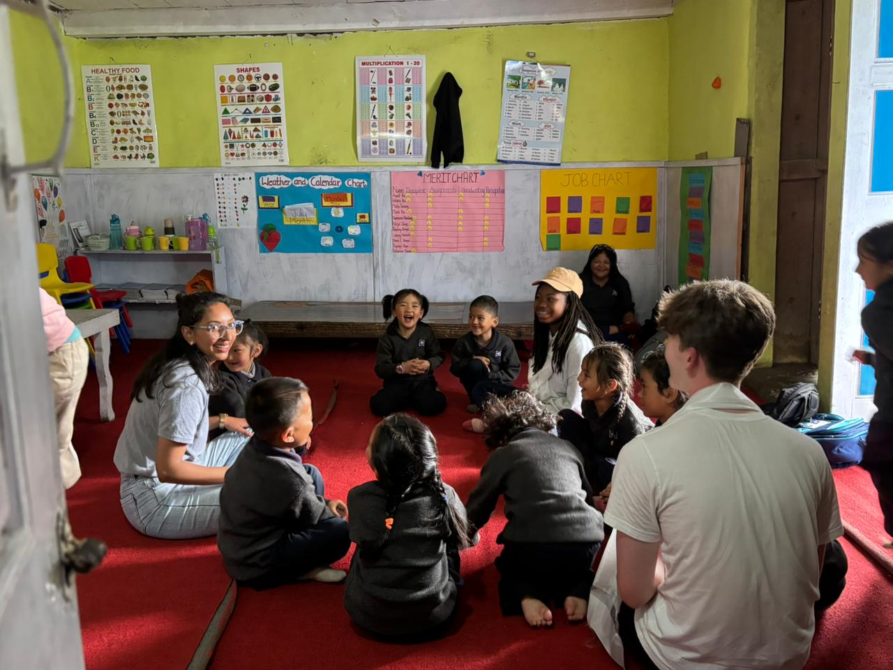 Student smiles widely at small children seated in circle for a lesson