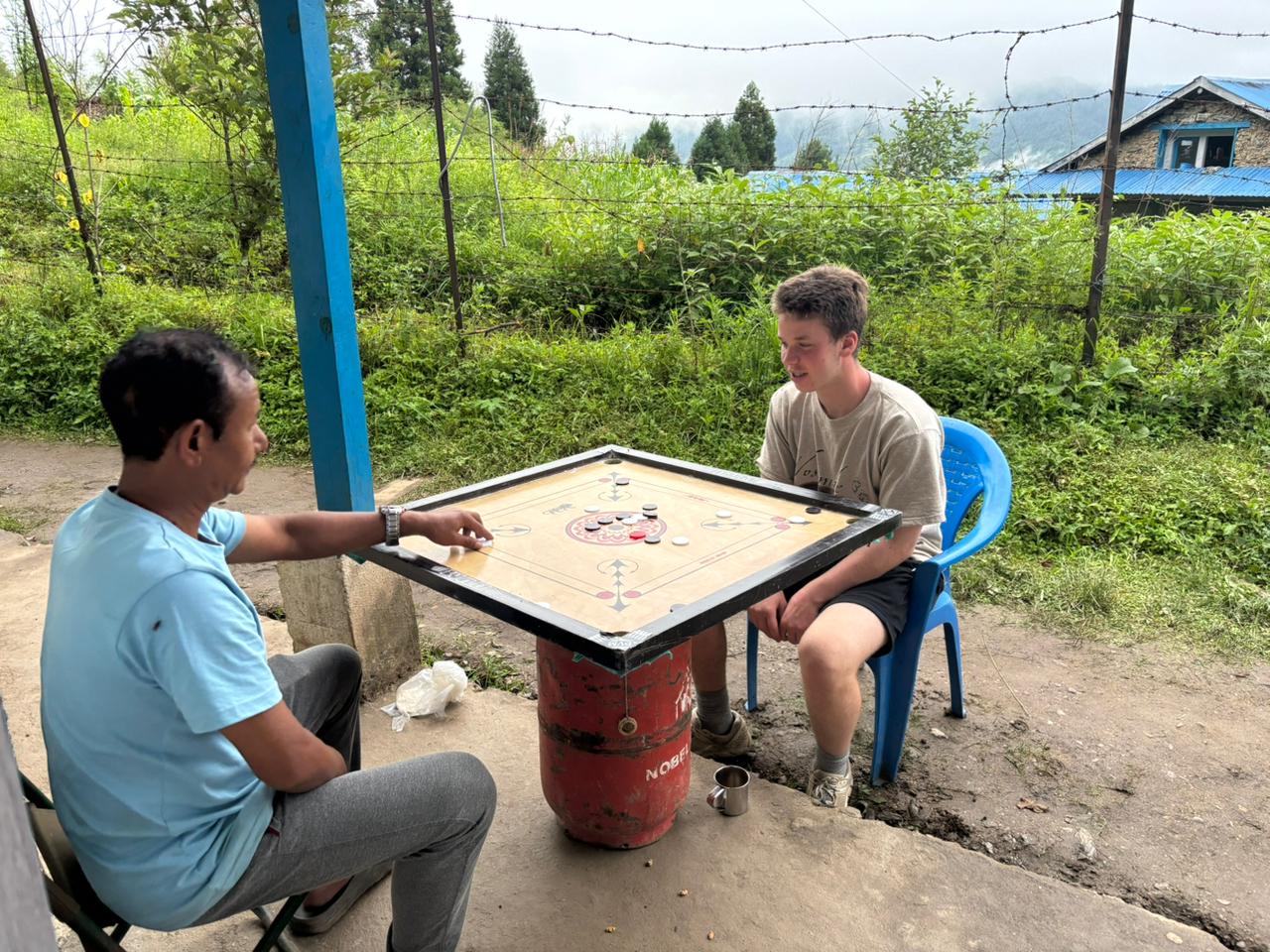 Student sits outside playing a board game with a local leader