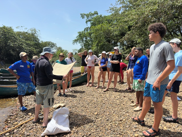 Students stand on the shore as leader talks