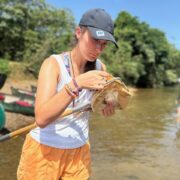 Student looks in net for species with river in background
