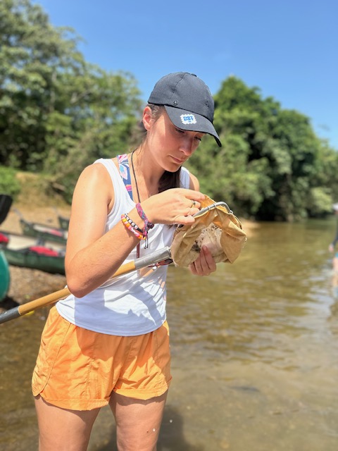Student looks in net for species with river in background