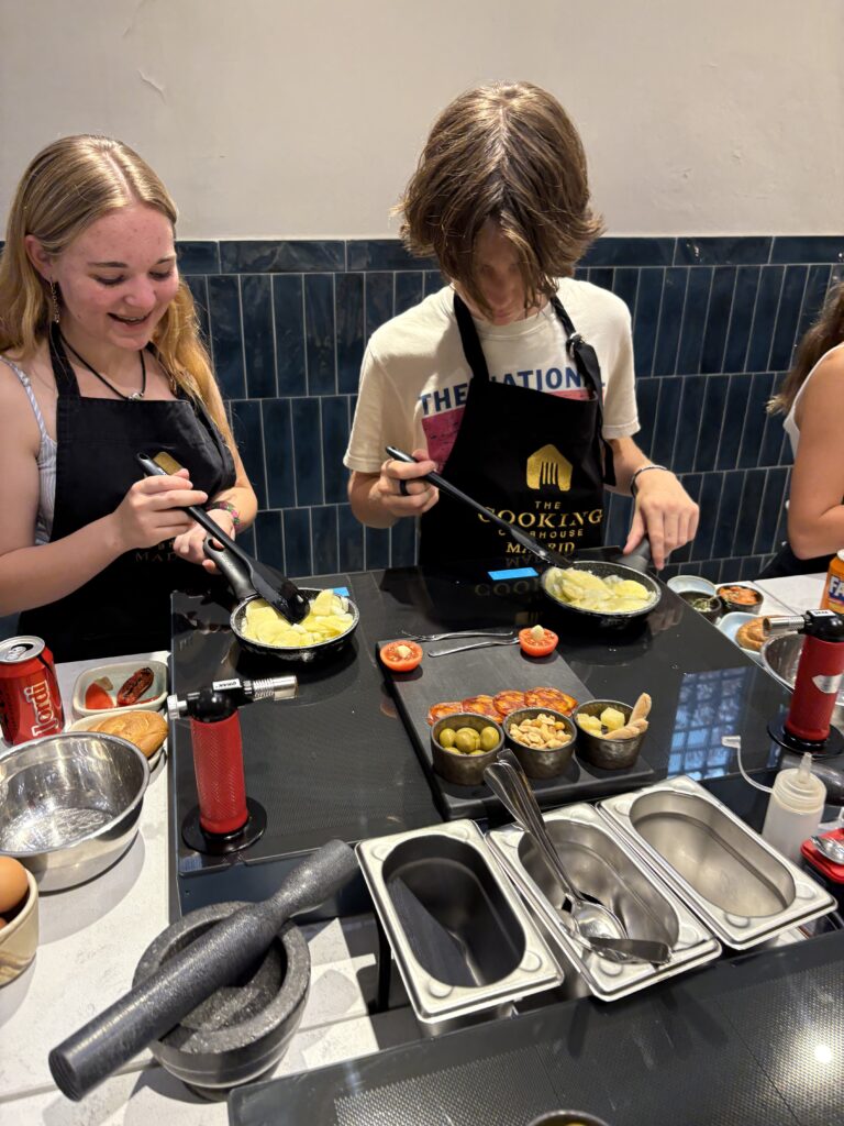 Two students cook egg dish in small black pans