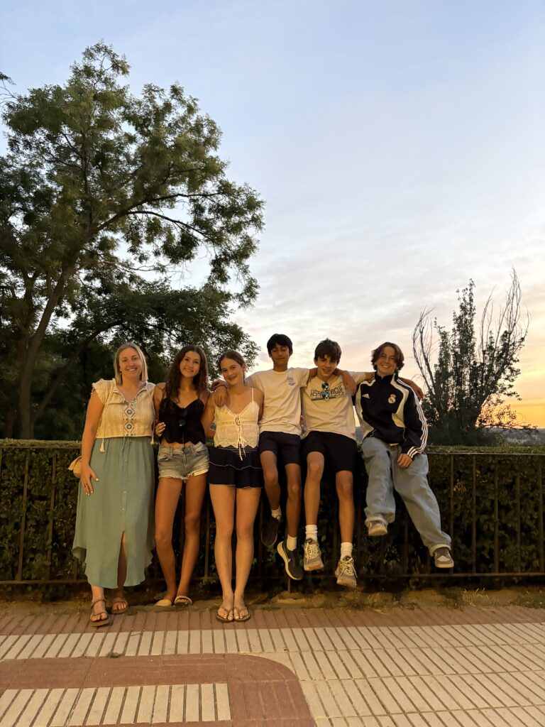 Students pose for a group photo outside at sunset